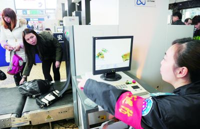 2月16日,长沙火车站,安检员透过安检扫描机检查旅客的行李.记者